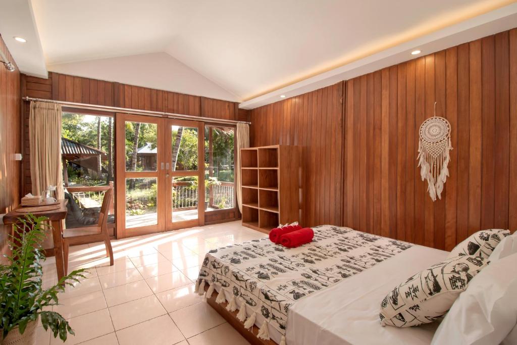 3WILL Bunaken Dive Resort في بوناكن: غرفة نوم عليها سرير ومخدة حمراء
