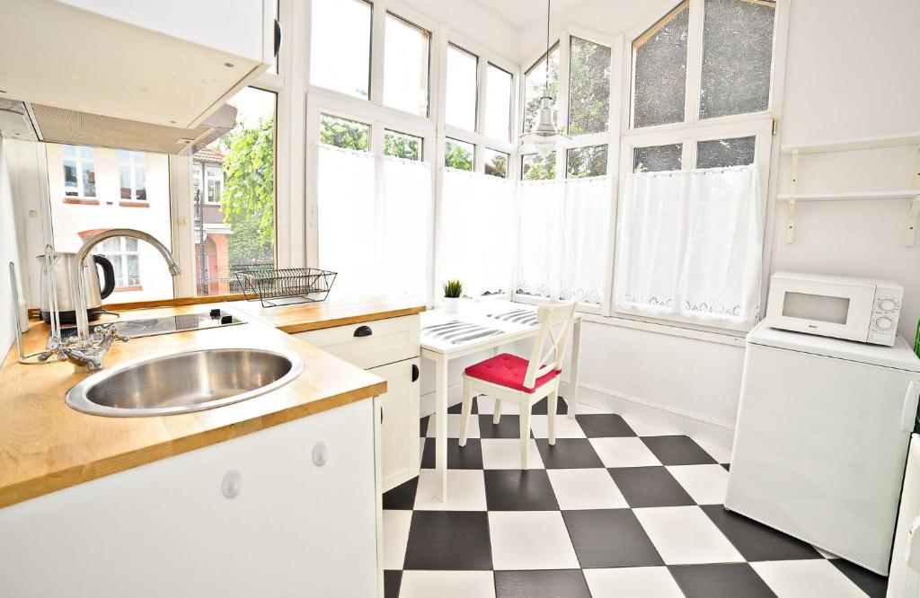 a kitchen with a black and white checkered floor at White Marina Apartment by Grand Apartments in Sopot