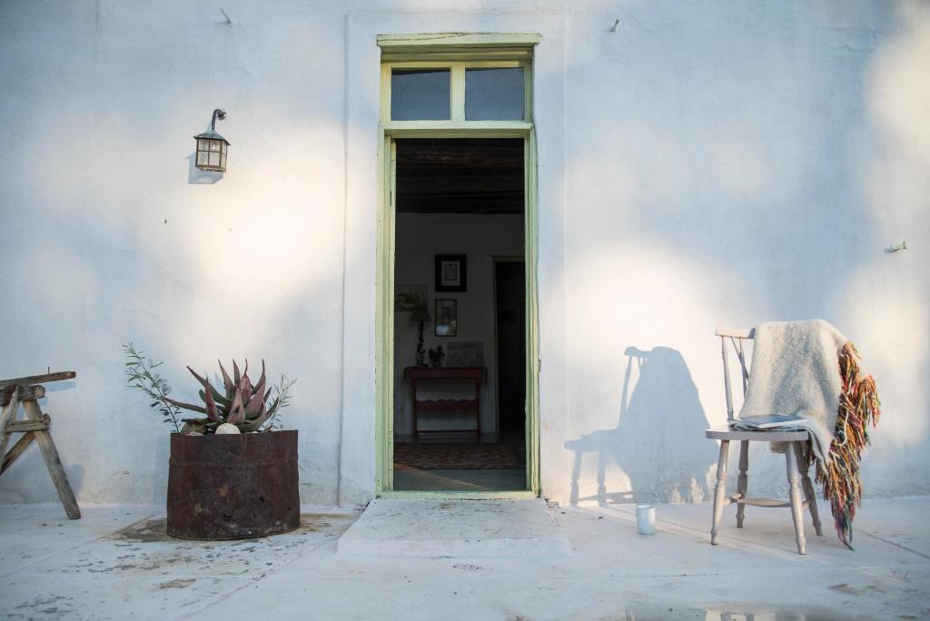 un edificio blanco con una silla y una puerta en African Relish - Akkedis Cottage, en Prince Albert