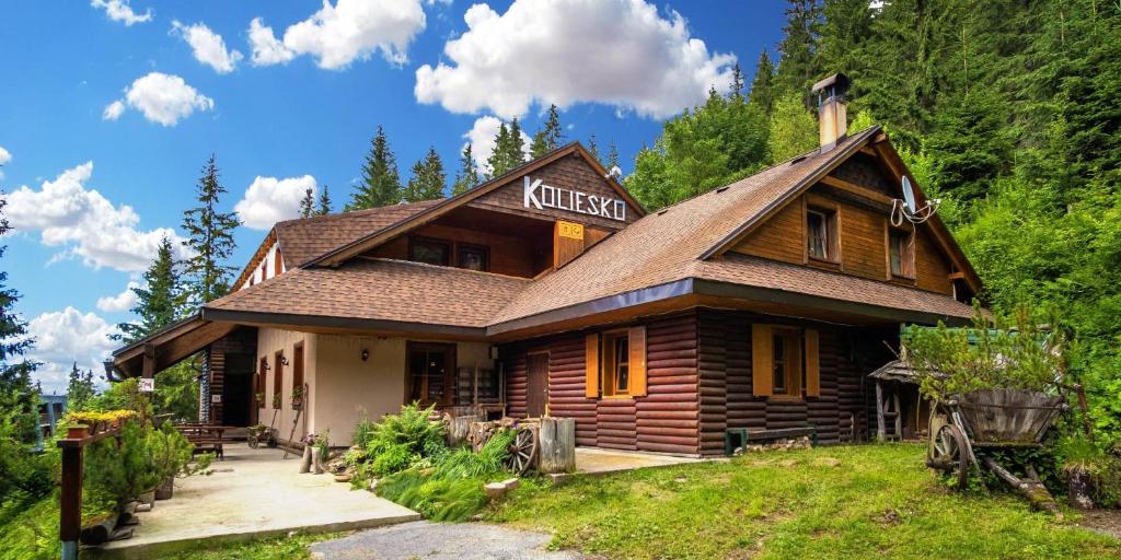 una baita di tronchi con un cartello sul lato di Chata Koliesko a Demänovská Dolina