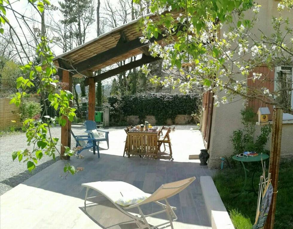 d'une terrasse avec des chaises et une table sous une pergola. dans l'établissement Maison 3 étoiles avec jardin pour familles, sportifs, curistes..., à Digne-Les-Bains