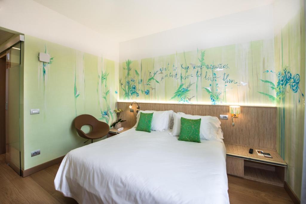 a bedroom with a large white bed with green pillows at Hotel Astoria Gallarate in Gallarate