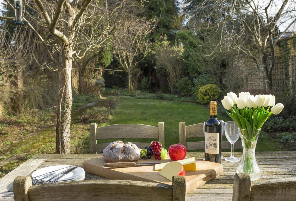 uma mesa de madeira com uma garrafa de vinho e flores em Fairfields em Moreton-in-Marsh