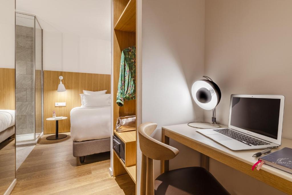 a room with a desk with a laptop and a bed at 9Hotel Republique in Paris