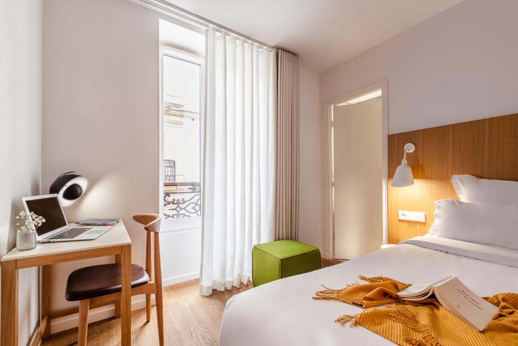 a hotel room with a bed and a desk and a window at 9Hotel Republique in Paris