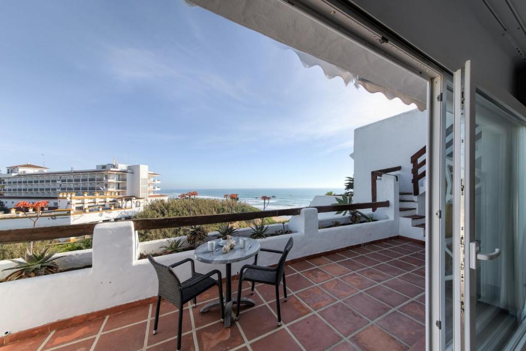 a balcony with a table and chairs and the beach at Villas Flamenco Beach Conil in Conil de la Frontera