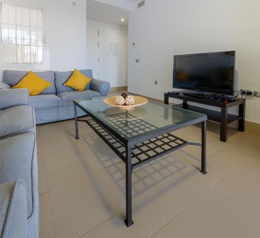 a living room with a blue couch and a tv at Villas Flamenco Beach Conil in Conil de la Frontera