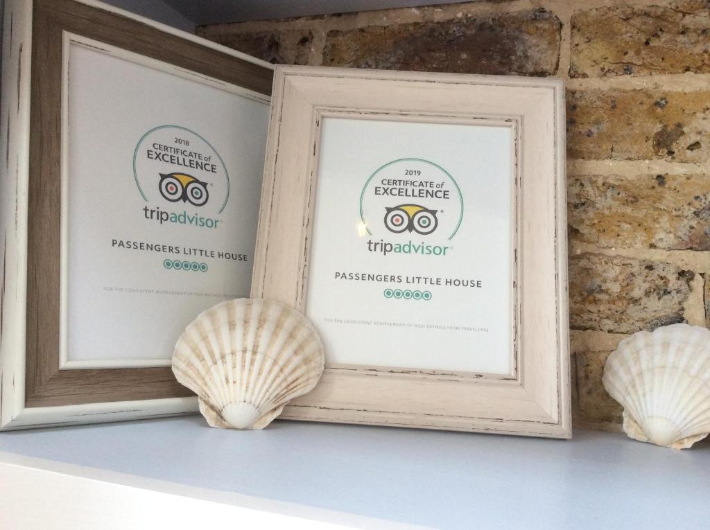 two framed signs on a shelf with seashells at Passengers House in Whitstable