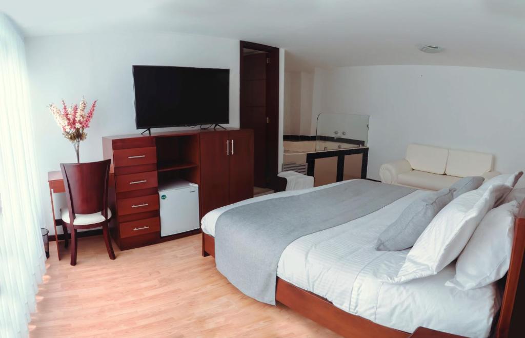 um quarto com uma cama, uma televisão e uma secretária em Nogal Suite Hotel em Pasto
