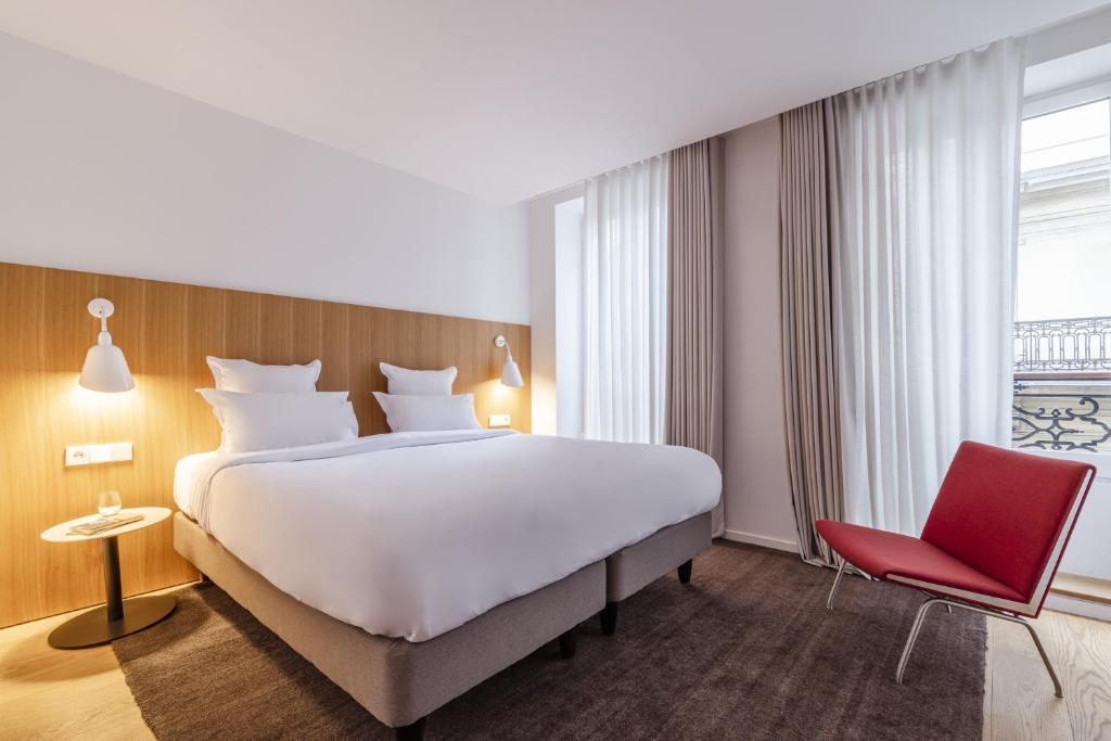 a hotel room with a large bed and a red chair at 9Hotel Republique in Paris