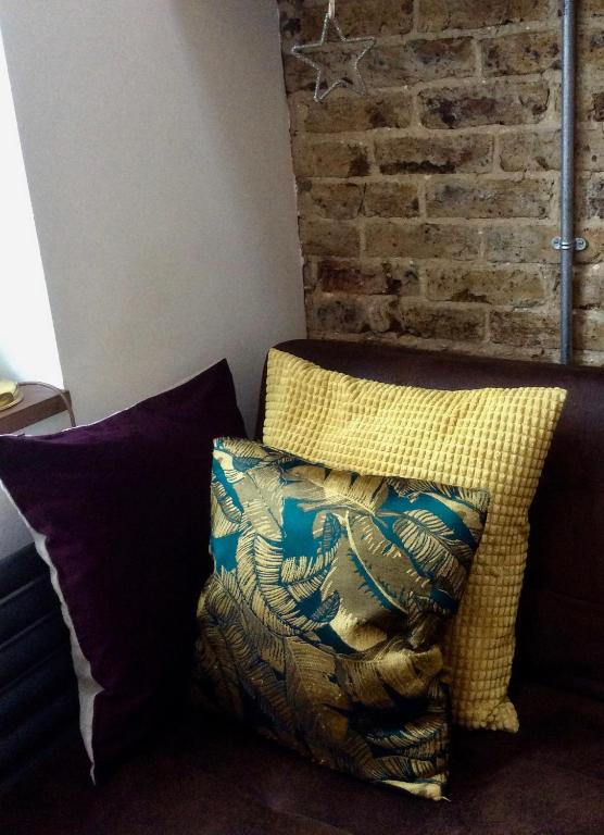 a pillow sitting on a couch next to a brick wall at Passengers House in Whitstable