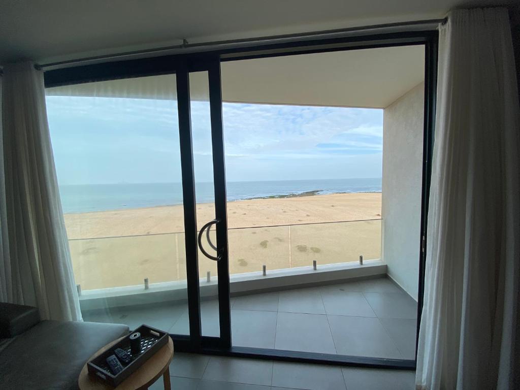 um quarto com uma grande janela com vista para a praia em Apartment 32, BAY VIEW SUITES em Langstrand