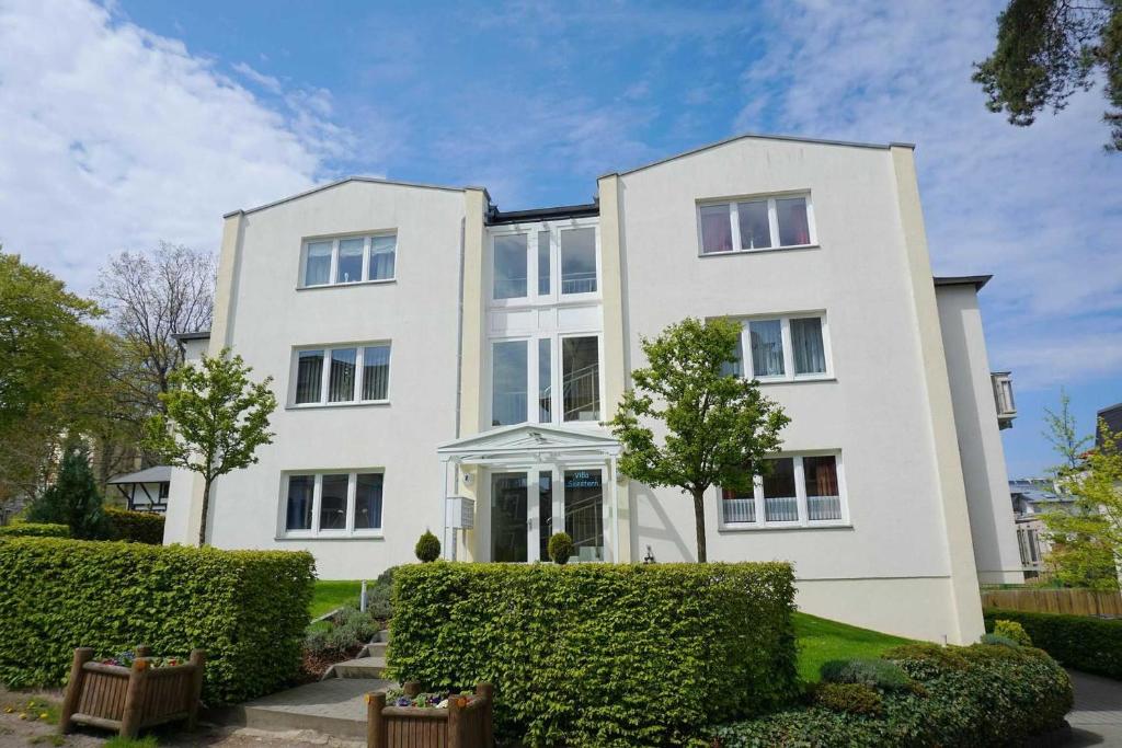uma casa branca com arbustos à frente em Villa Seestern Wohnung 9 em Neuhof