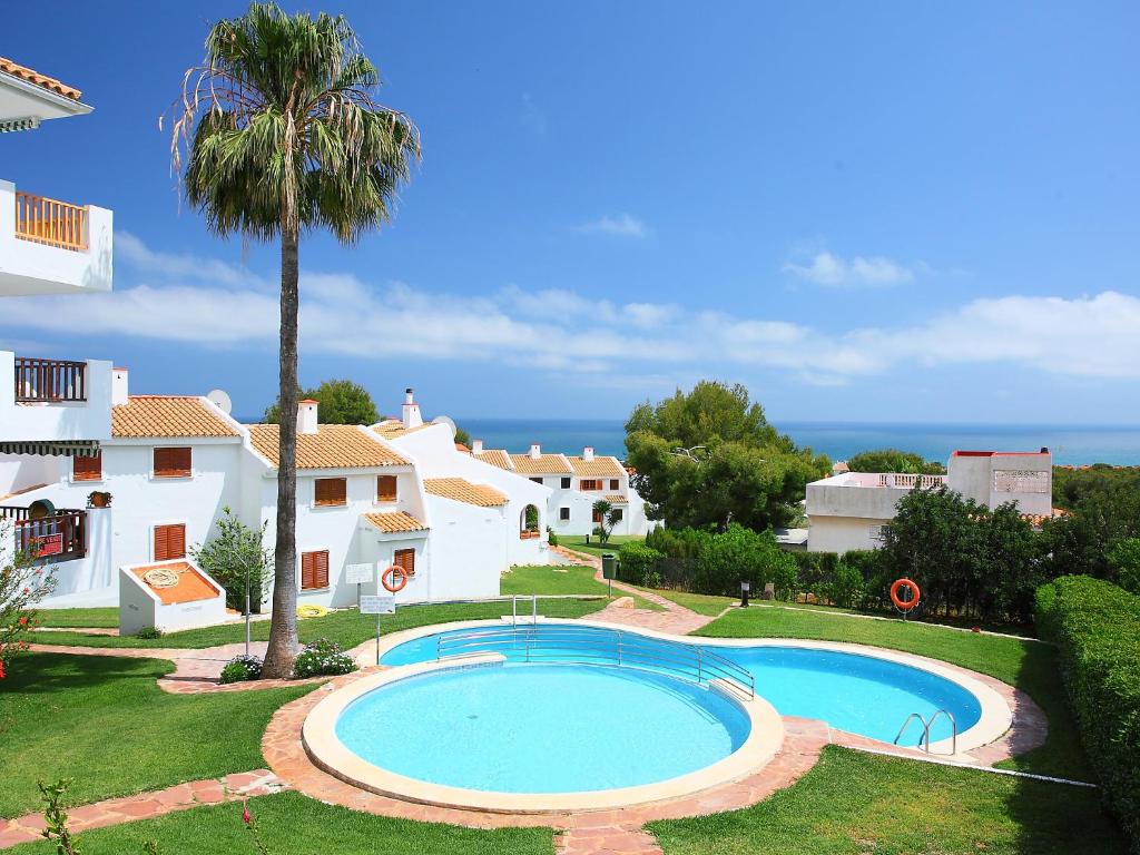 a villa with a swimming pool and a palm tree at Holiday Home Las Haciendas by Interhome in Alcossebre