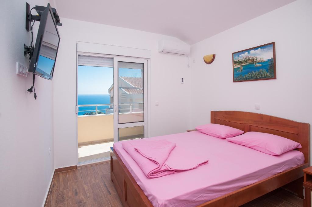 烏爾齊尼的住宿－Apartments Onyx，一间卧室配有一张带粉色床单的床和一扇窗户。