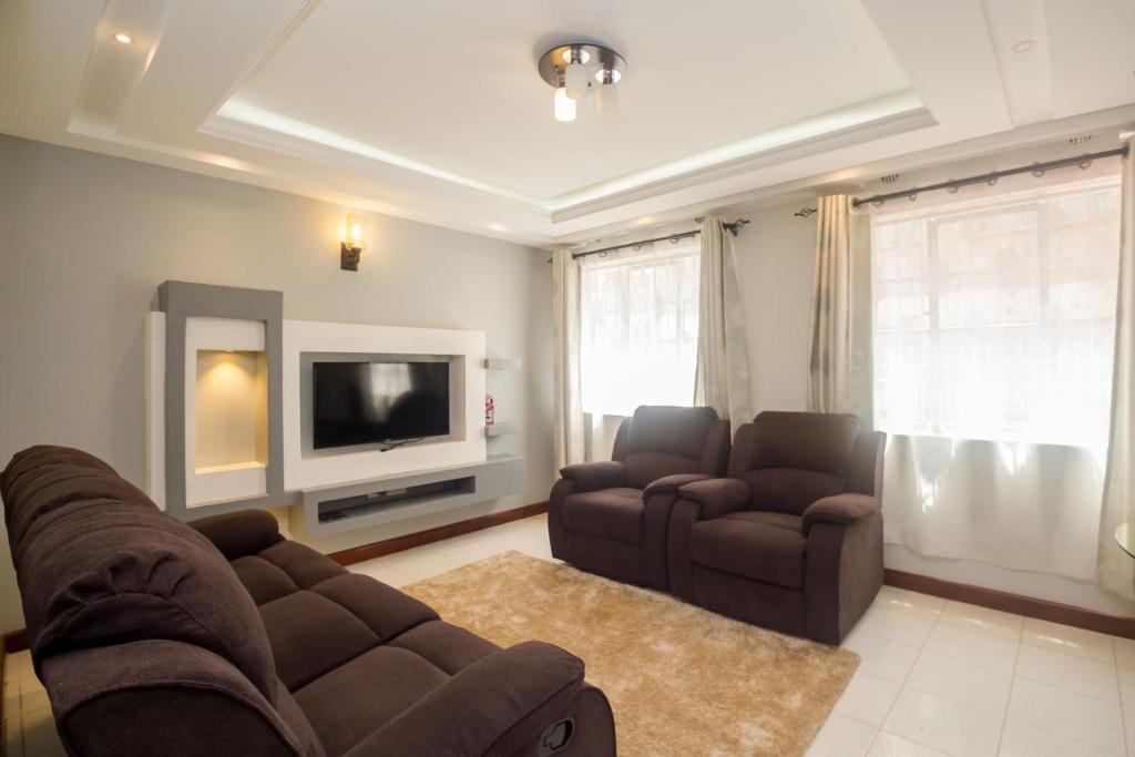 uma sala de estar com um sofá e cadeiras e uma televisão em Esterina Suites em Nairobi