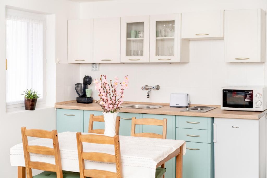 une cuisine avec des placards bleus et une table avec des chaises dans l'établissement Menta Porta, à Zengővárkony