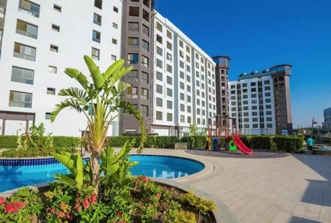 un grand immeuble avec une aire de jeux et une piscine dans l'établissement The Resort Chalet- Porto New Cairo, au Caire
