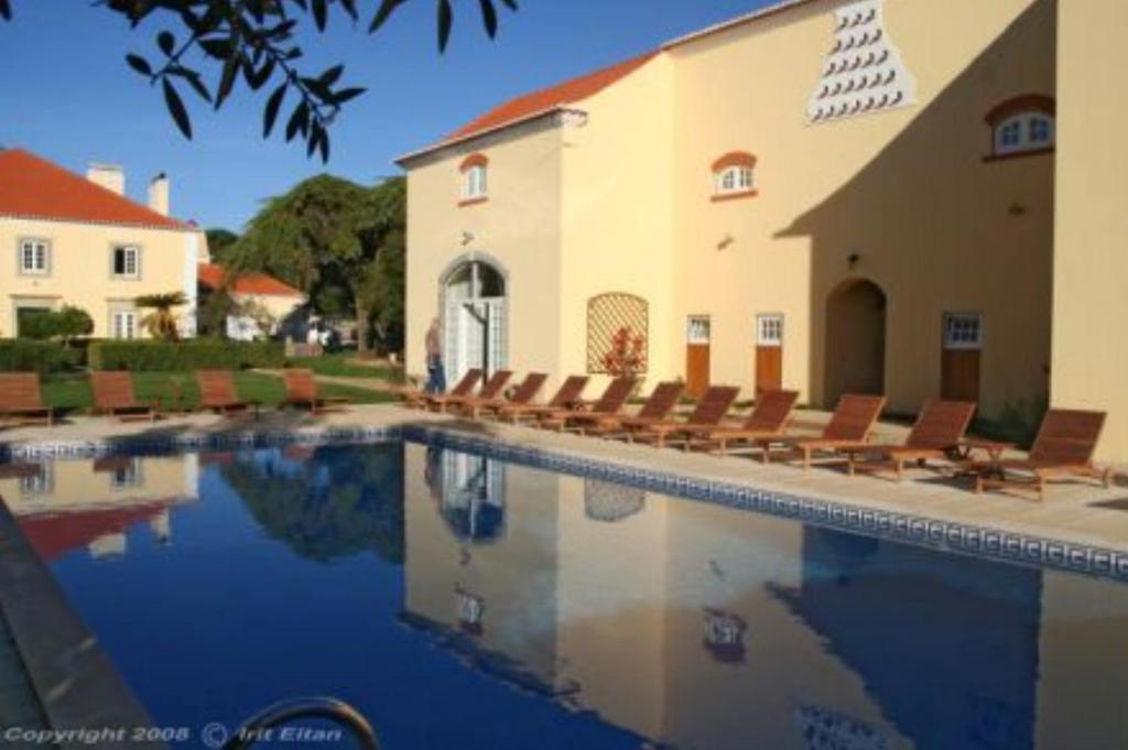 a swimming pool in front of a building with chairs at Quinta Do Scoto in Sintra