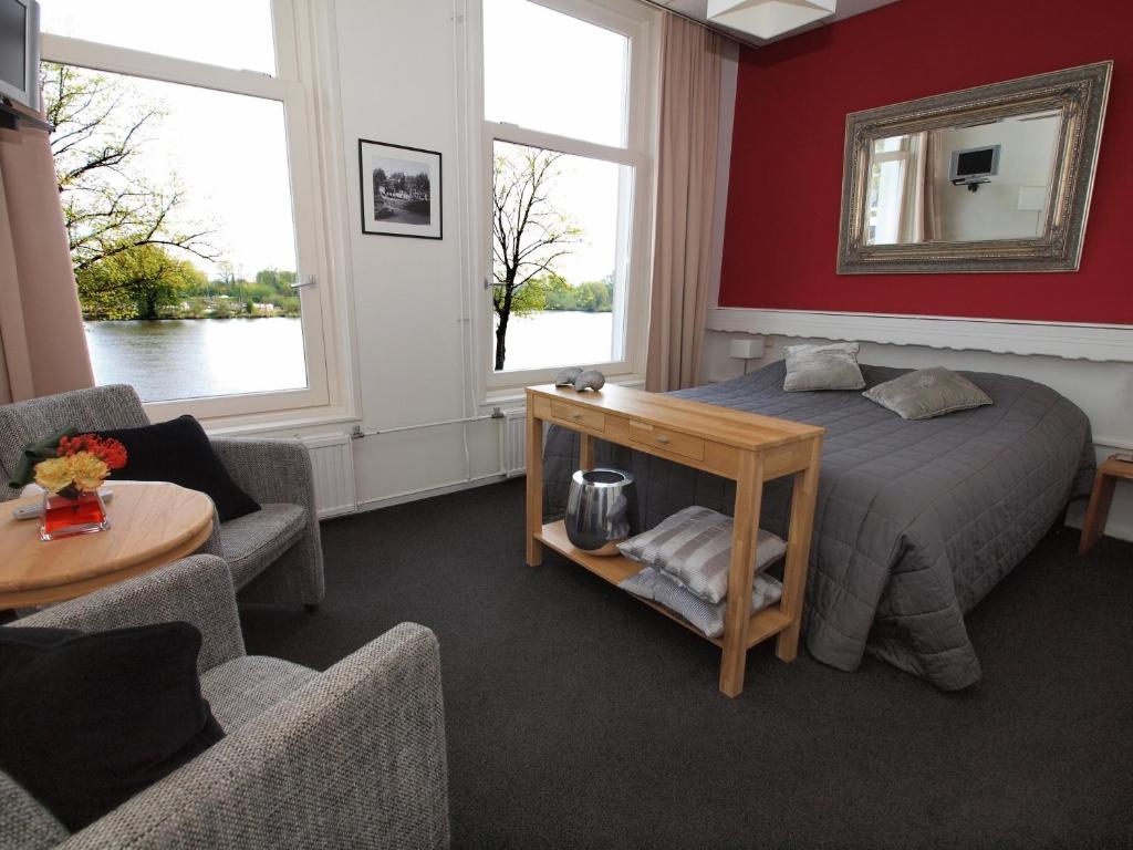 a bedroom with a bed and two chairs and a table at Hotel van Dijk in Kampen