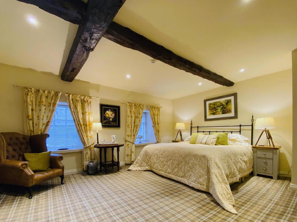 Schlafzimmer mit einem Bett, einem Stuhl und Fenstern in der Unterkunft The Moon Inn at Stoney Middleton in Stony Middleton