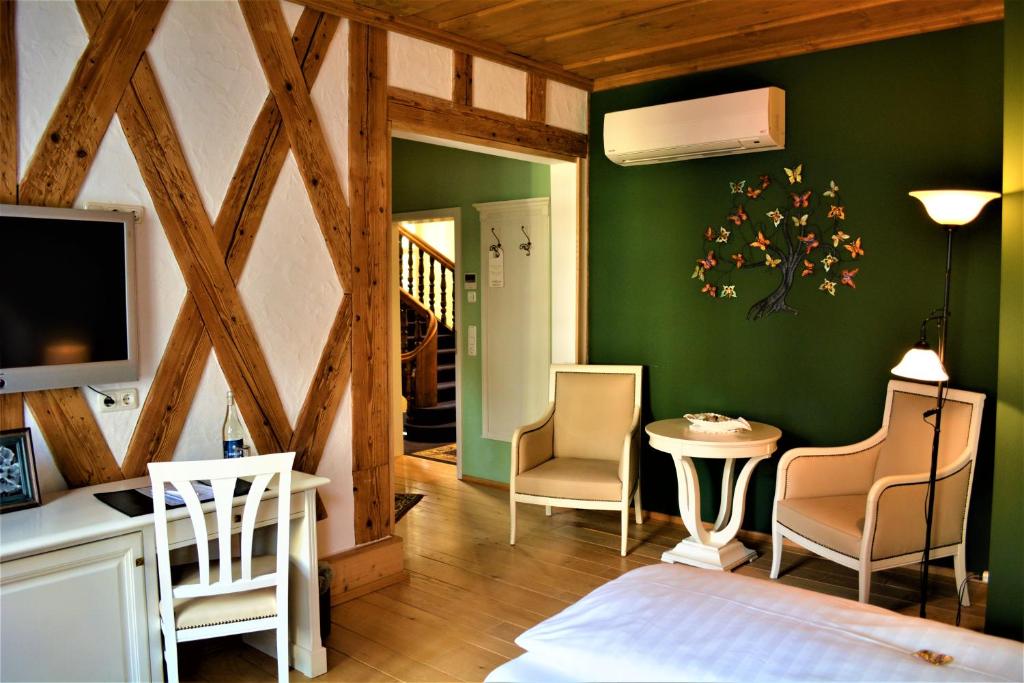um quarto com paredes verdes e uma mesa e cadeiras em Die Kronacher Stadthotels em Kronach