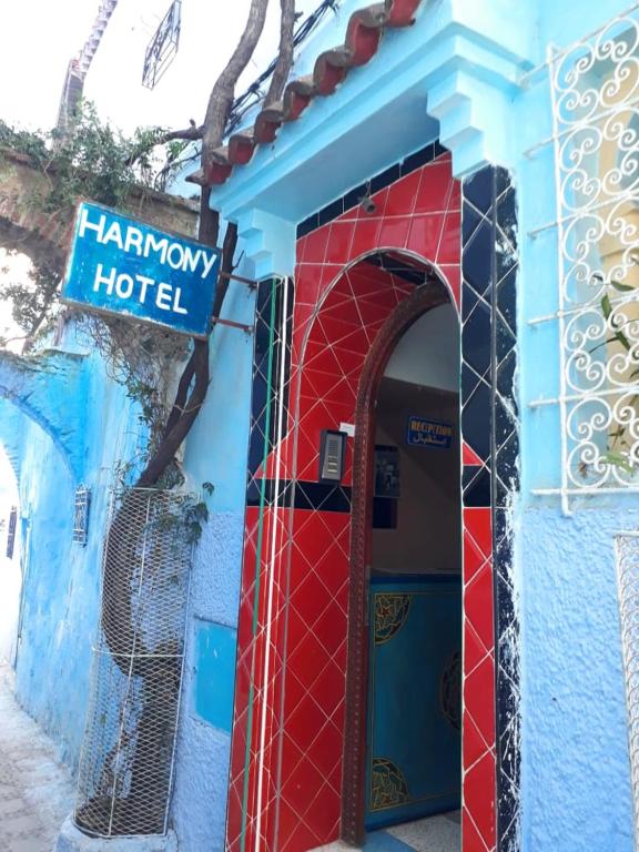 Harmony Hotel في شفشاون: مبنى ازرق واحمر مع علامة الفندق