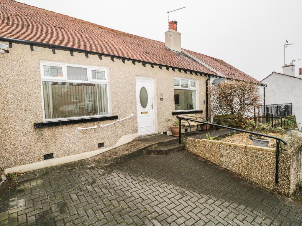 a brick house with a white door and a patio at Cosy Bee in Morecambe