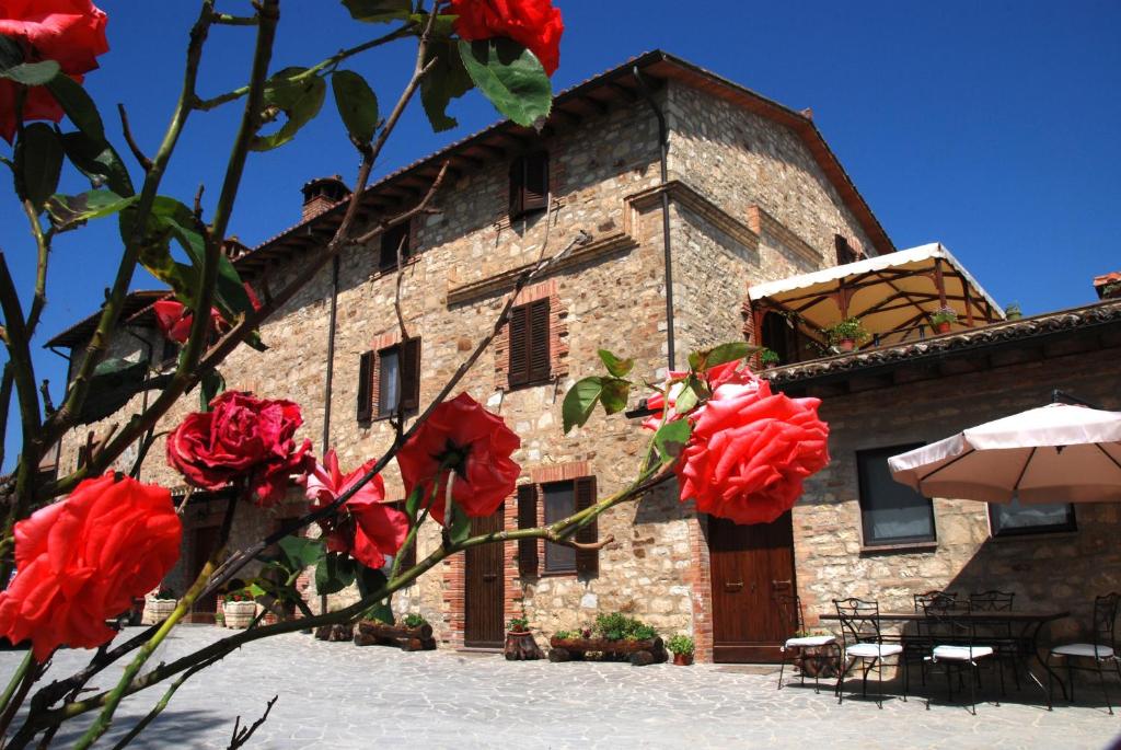 a stone building with red roses in front of it at Antico Casolare in Marsciano