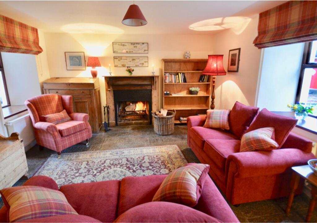 a living room with red furniture and a fireplace at Delphi Lodge in Leenaun