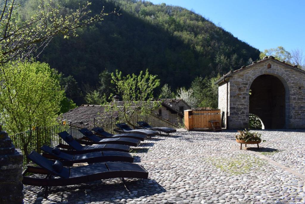 a row of chairs sitting in a courtyard with a mountain at Borgo Corniola B&B Naturista in Marradi