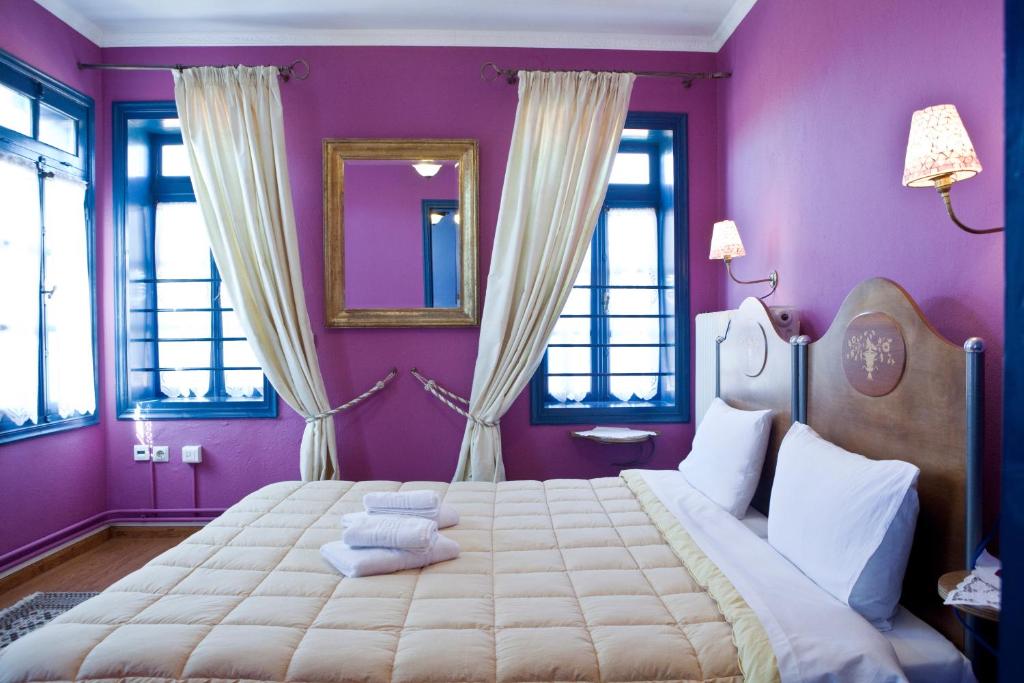 a bedroom with a large bed with purple walls and windows at House Mitsiou Traditional Inn in Arnaia