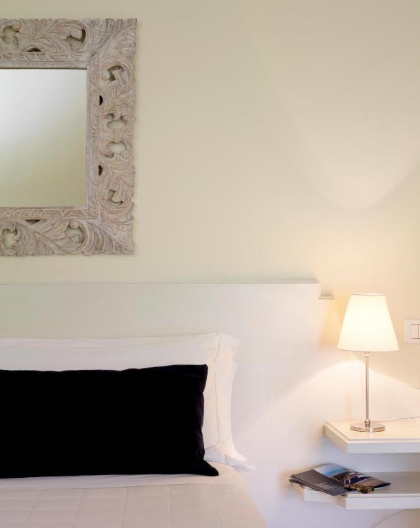 a white bedroom with a black pillow and a mirror at Hotel Sina Astor in Viareggio