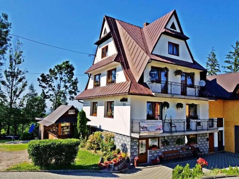 une grande maison blanche avec un toit marron dans l'établissement Nad Grapą, à Gliczarów