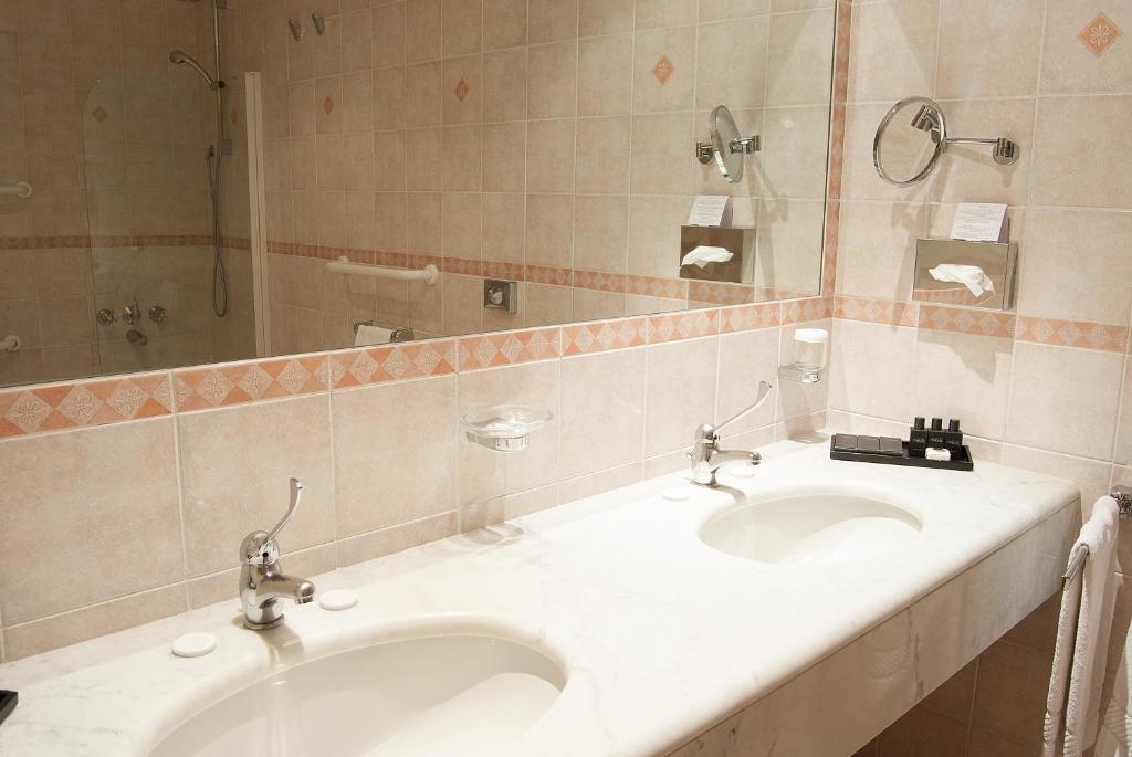 a bathroom with two sinks and a large mirror at Hotel Sina Astor in Viareggio