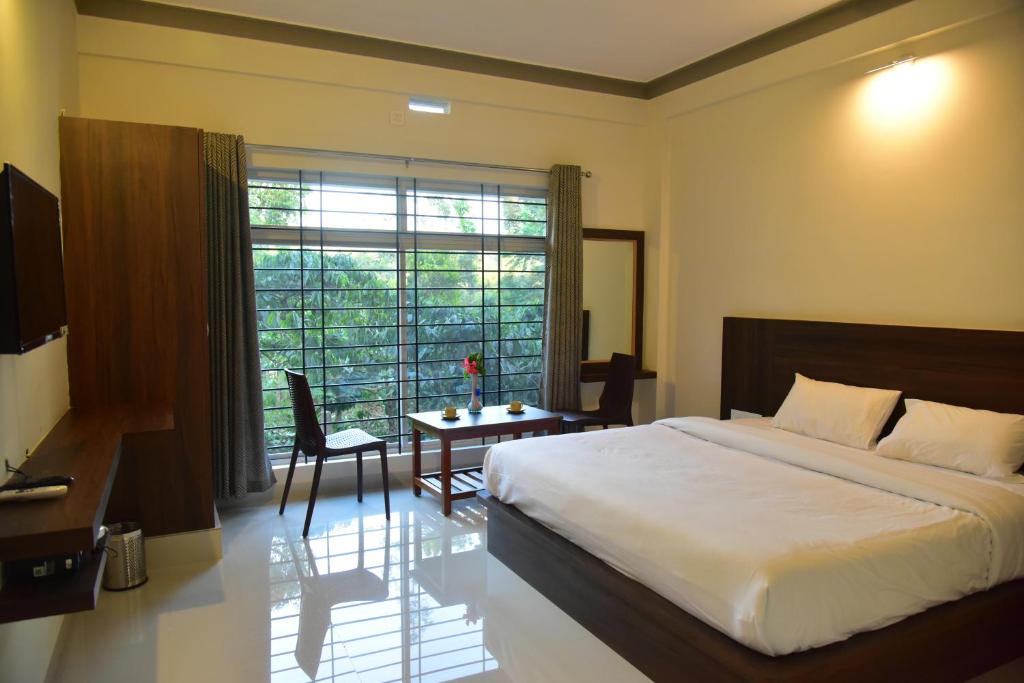a bedroom with a bed and a table and a window at Grand Misty Heaven in Madikeri