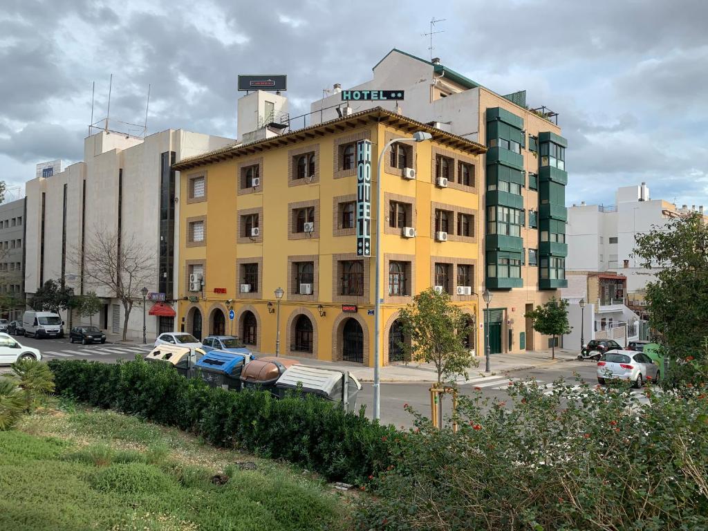 un edificio amarillo con coches estacionados en un estacionamiento en SunDos Feria Valencia, en Valencia