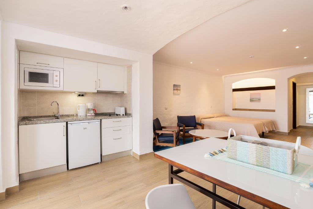 a kitchen and a living room with a table and chairs at Apartamentos Borda D´Agua in Albufeira