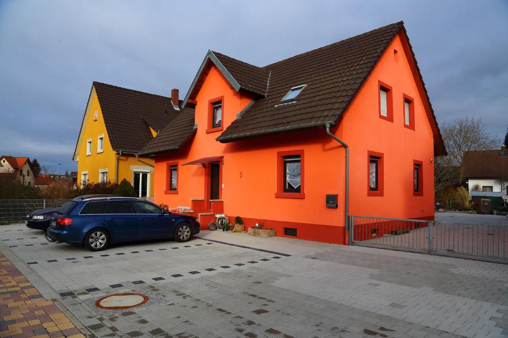 une voiture bleue garée devant une maison orange dans l'établissement Ferienwohnung Petra, à Rust