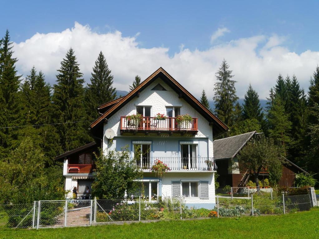 a white house with a balcony and trees at Haus zur Klamm in Berg im Drautal