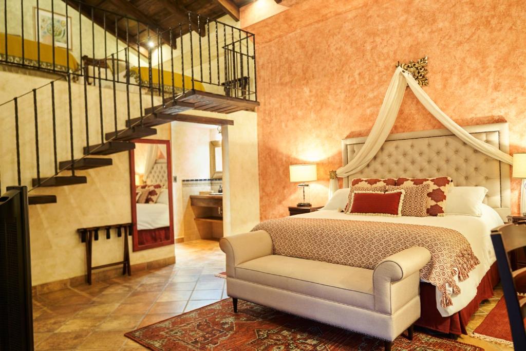1 dormitorio con 1 cama grande y una escalera en Casa Faustina Boutique Hotel, en Antigua Guatemala