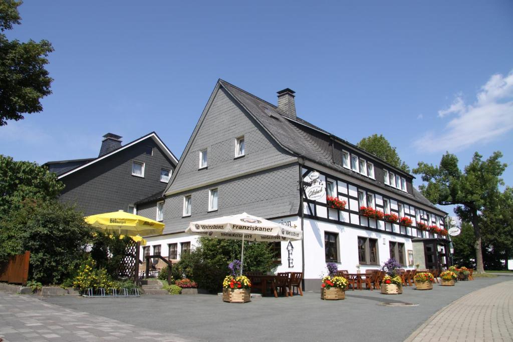 een gebouw met tafels en stoelen ervoor bij Ferienwohnungen Landgasthof Gilsbach in Winterberg