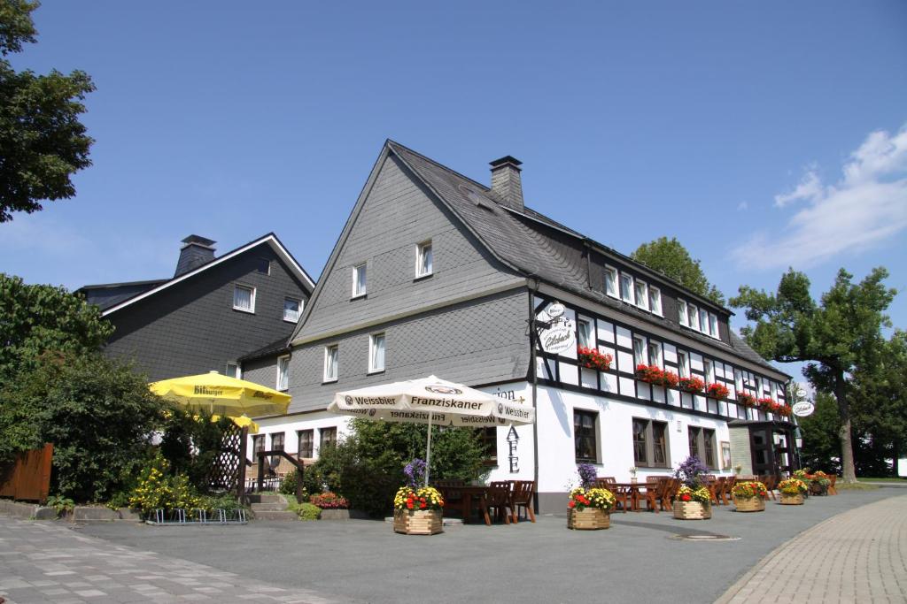 ein Gebäude mit Tischen und Stühlen davor in der Unterkunft Ferienwohnungen Landgasthof Gilsbach in Winterberg