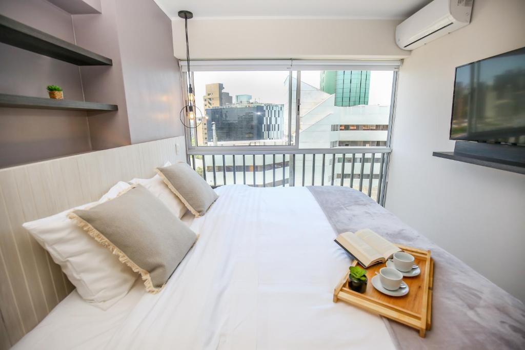 Un dormitorio con una gran cama blanca y una ventana en Trendy Host Black - San Isidro, en Lima