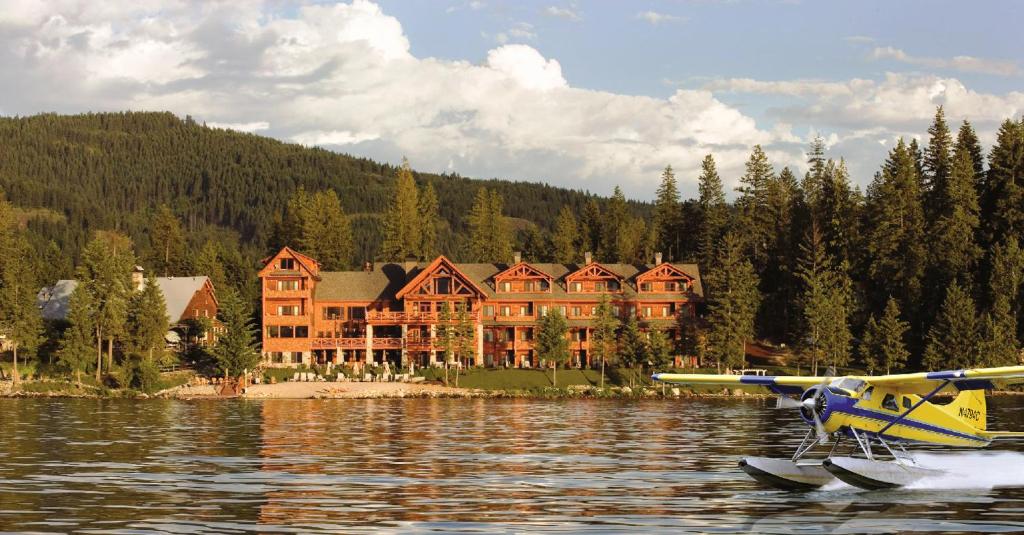 a plane in the water in front of a large house at Lodge at Sandpoint in Sandpoint