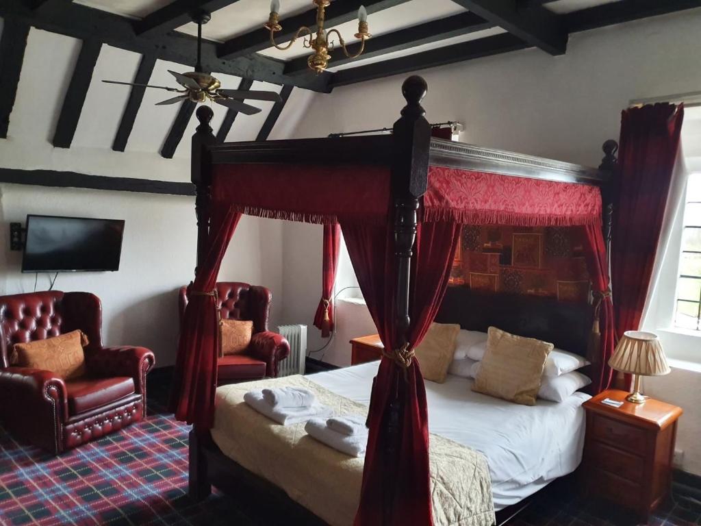 a bedroom with a canopy bed and two chairs at Old Court Hotel & Apartments in Symonds Yat