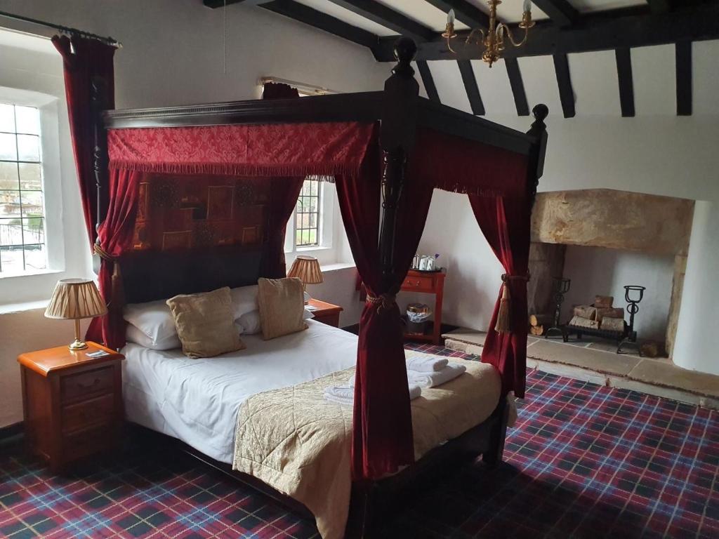 a bedroom with a canopy bed with red curtains at Old Court Hotel & Apartments in Symonds Yat