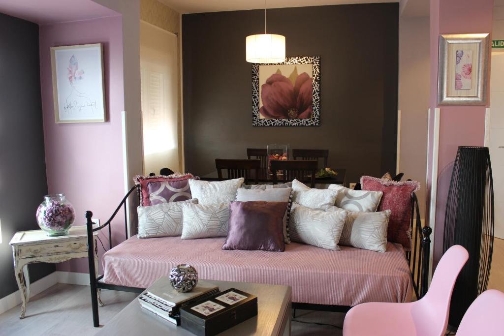 Apartamentos Nundinae في ماردة: غرفة نوم مع سرير وملاءات ووسائد وردية