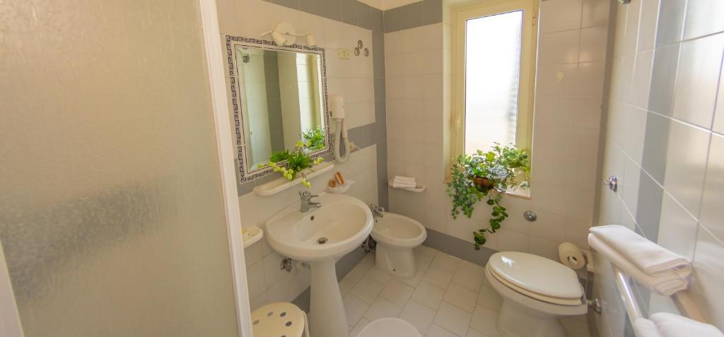 a white bathroom with a sink and a toilet at Hotel Solaria in Rodi Garganico