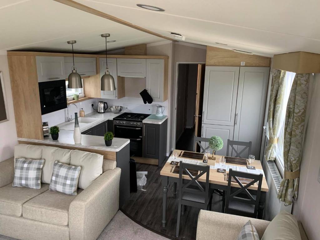 una cucina e un soggiorno con divano e tavolo di 3 bed presitage caravan Doniford Bay a Watchet